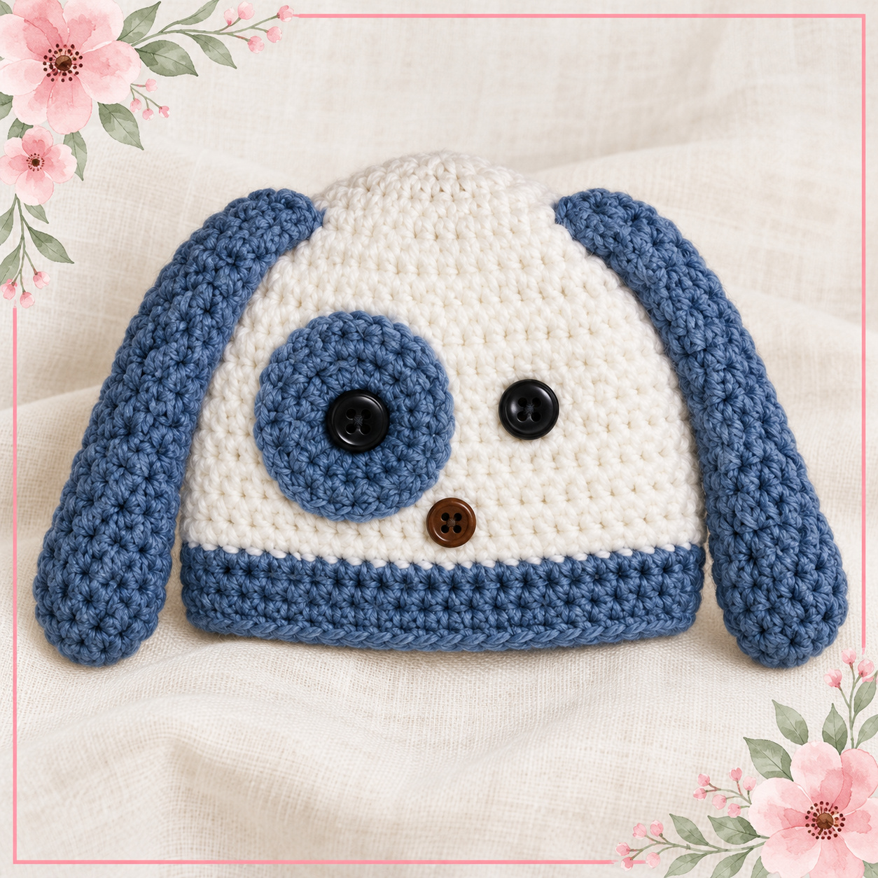 Crochet Puppy Dog Hat in white with long dusty-blue floppy ears, a dusty-blue eye patch and trim, black button eyes and a brown button nose